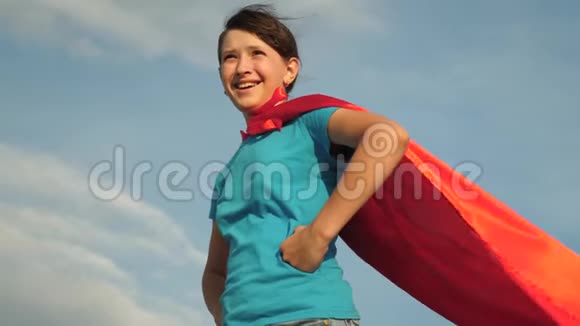 美丽的女孩超级英雄穿着红色斗篷站在田野上斗篷随风飘扬慢动作特写镜头女孩的梦想视频的预览图