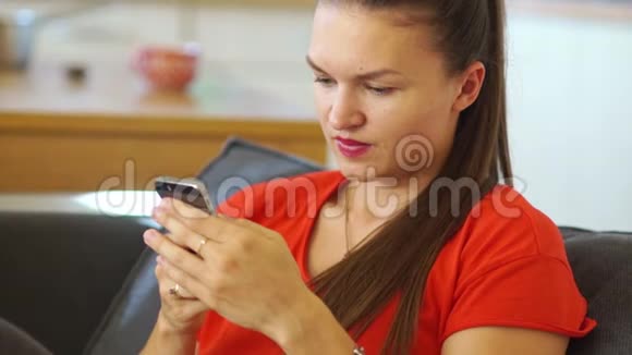一个穿着红色裙子的漂亮女孩在她的手机上写了一条信息然后他看着框架笑得很宽社会视频的预览图
