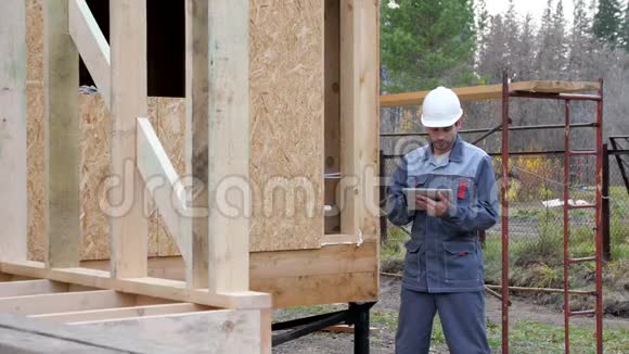 房子前面的白人工人建筑师或建筑商检查半建木框架房屋的计划一个建筑商视频的预览图