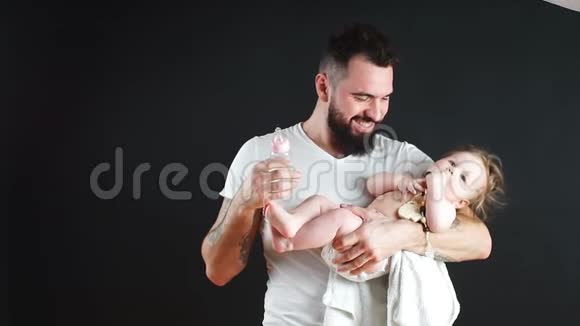 嬉戏的父亲带着他微笑的婴儿在蓝色背景的脖子上视频的预览图