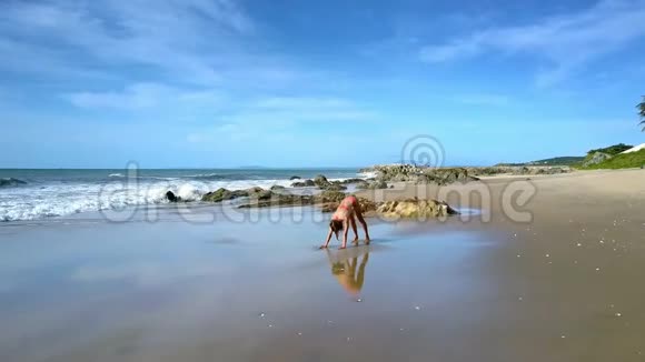 蓝天下海滩瑜伽筒中的女孩伸展身体视频的预览图
