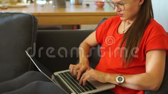一个穿红色裙子的女孩的特写镜头正在用笔记本电脑她累了休息一下摘下眼镜视频的预览图