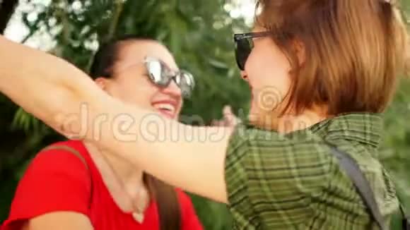 两个戴墨镜的漂亮少女抱着笑在公园散步周末暑假视频的预览图