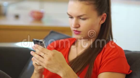 黑发女人拿着手机写着信息微笑着专注于女孩手中的手机视频的预览图
