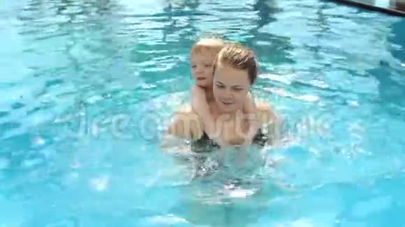 特写快乐妈妈教儿子在游泳池里游泳暑假视频的预览图