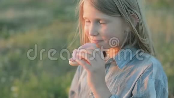 小女孩正在吃三明治微笑着看着夕阳视频的预览图