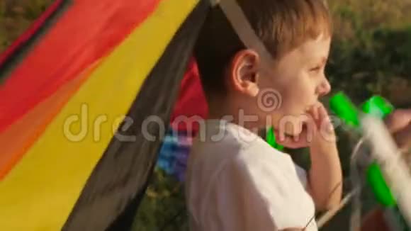 小男孩脸上带着鬼脸手里拿着彩色风筝把手视频的预览图