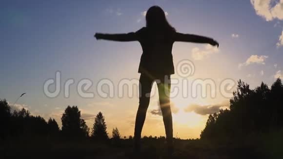 年轻女子在夕阳下慢动作跳跃的剪影视频的预览图