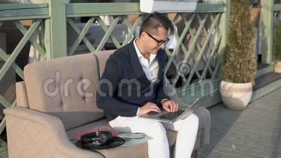 一个男人和朋友在阳台上的笔记本上写字视频的预览图
