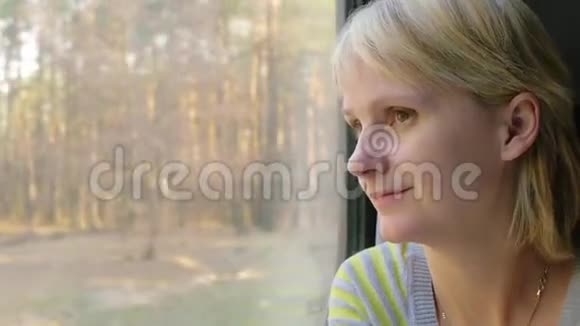 一位年轻女子坐火车旅行望着窗外的风景视频的预览图