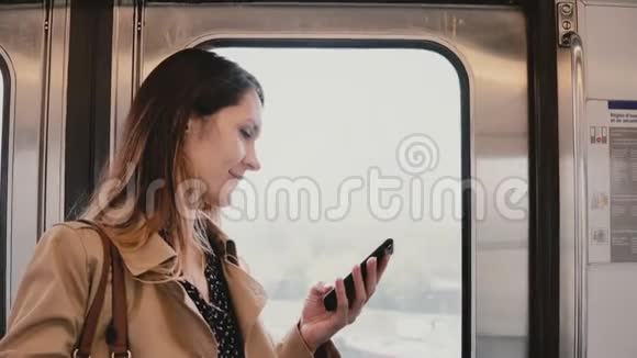 地铁车里有智能手机的女商人相当年轻的女性通勤者使用信使应用程序在线无线5G4K视频的预览图