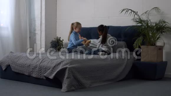 可爱的多民族女孩在床上玩玩具视频的预览图