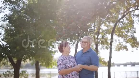 快乐的老年夫妇在户外恋爱阳光花园里快乐的老年夫妇视频的预览图