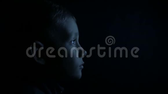 黑暗中的孩子正在看电视视频的预览图
