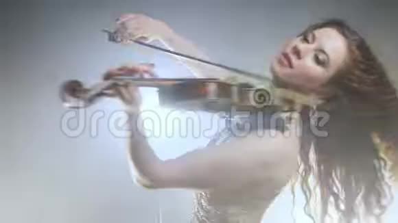 一位留着长发的小提琴女在闪光和烟雾的背景下转过身玩小提琴视频的预览图