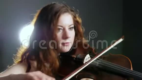 小提琴家女孩在聚光灯背景下的工作室里用木琴演奏的肖像视频的预览图