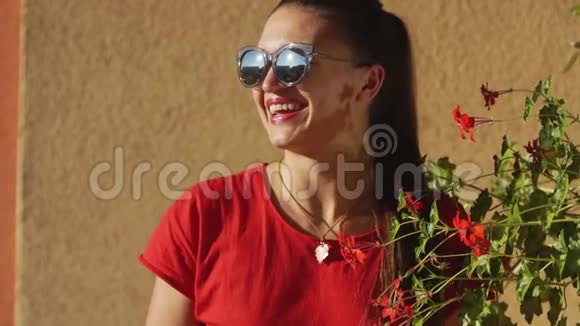年轻时尚的女士穿着红色夏装站在酒店的露台上长发太阳镜民族耳环视频的预览图