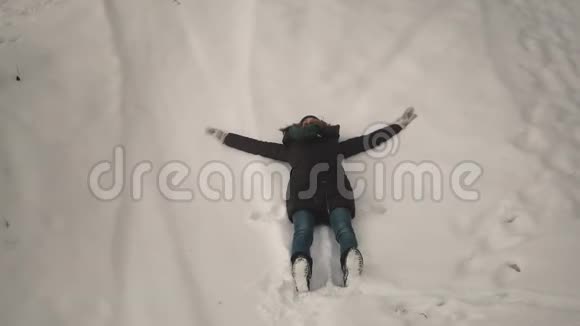 女孩在森林里的雪地上做雪天使视频的预览图