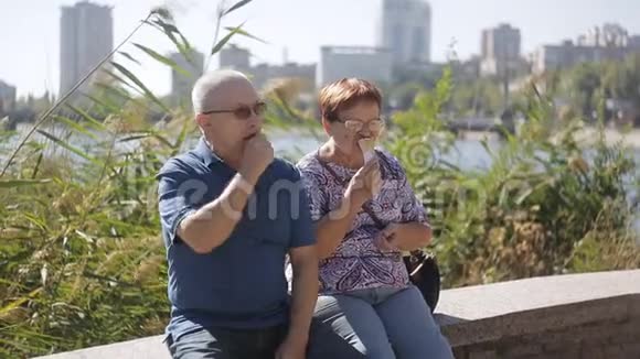 一对老夫妇坐在长廊上吃冰淇淋聊天一对老情人在聊天吃点冰视频的预览图