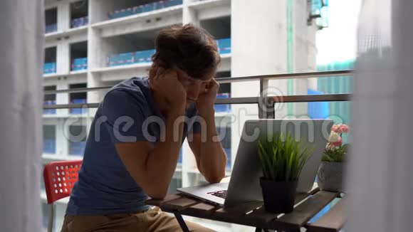 年轻人坐在阳台上拿着笔记本在附近的一个建筑工地上大声喧哗视频的预览图