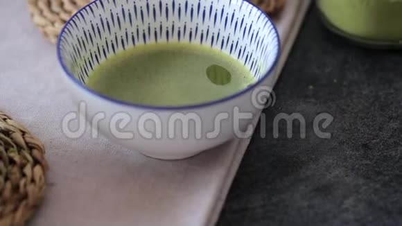 将绿茶抹茶混合在蓝色表面的碗中视频的预览图