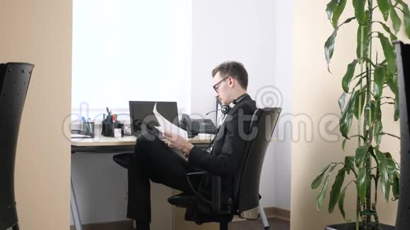 穿西装的年轻人正坐在办公室里疲惫不堪摘下眼镜靠在椅子上60英尺高视频的预览图