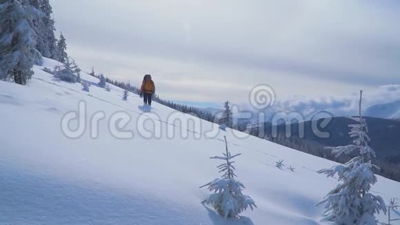 一个游客走过山上的雪视频的预览图