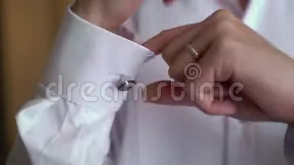 男性手在白色衬衫的背景上袖子衬衫与袖扣和手表穿上特写视频的预览图
