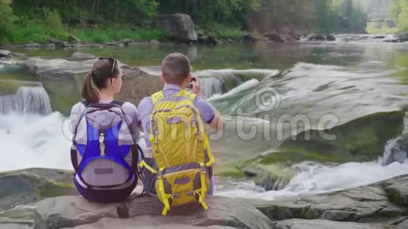 一对年轻的游客欣赏这条山河一个男人用智能手机为这条河拍照视频的预览图