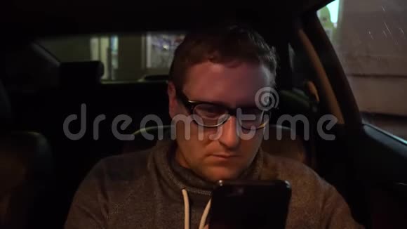 年轻的司机在车里用智能手机视频的预览图