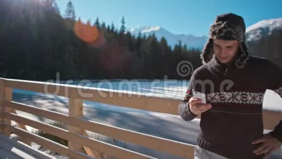 在美丽的山地公园冬天帅哥使用智能手机户外活动视频的预览图