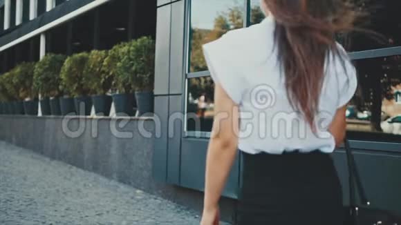 年轻漂亮聪明的商务女孩穿着商务服走路在这段时间里她手里拿着包视频的预览图