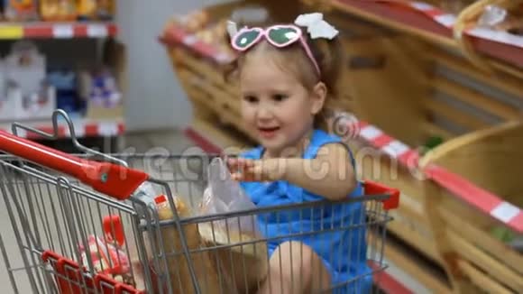 小女孩坐在超市的手推车里吃东西拿着面包婴儿购物视频的预览图
