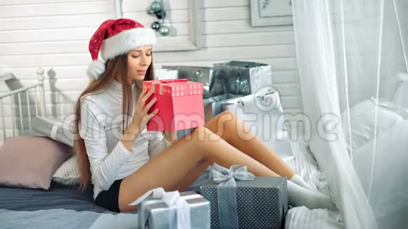 戴着圣诞帽的漂亮女人对红盒子里的惊喜感到惊讶视频的预览图