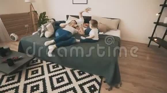 可爱的家庭在家里的床上缓慢地在卧室里玩耍顶部视图视频的预览图