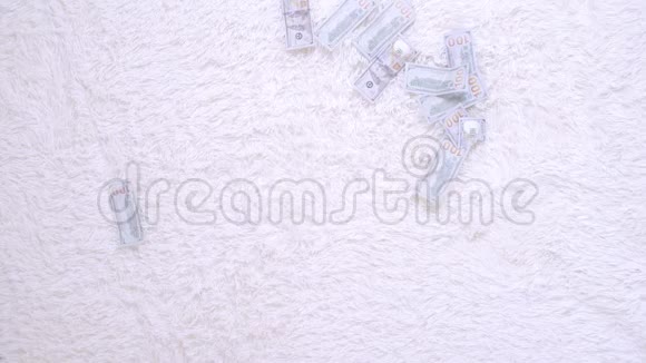 许多钞票在白色的床上缓慢地在空中飞舞巨大的财富慢动作俯视视频的预览图