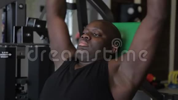 强壮的非裔美国人在训练机上摆动他的手臂肌肉视频的预览图