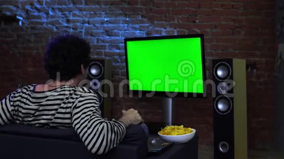 在绿色电视上看精彩节目的男人视频的预览图