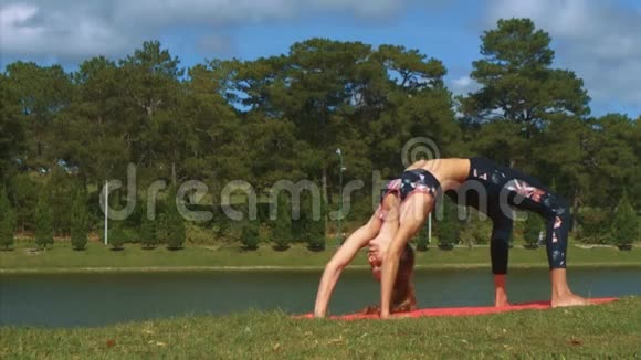 女人站在湖边草滩的瑜伽姿势视频的预览图