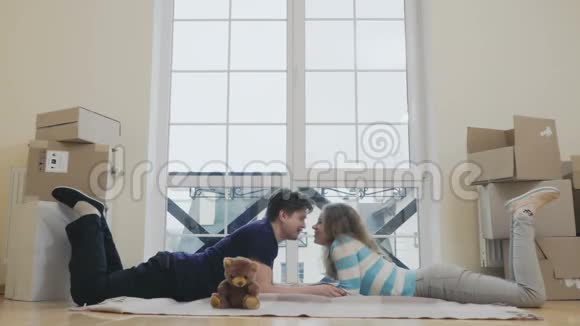 幸福的一对情侣躺在新房子的地毯上微笑着拍照视频的预览图