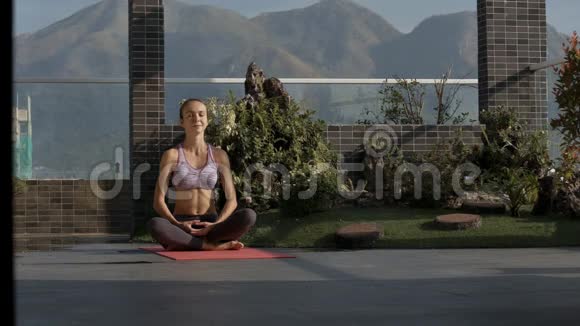 女孩坐在阳台上的瑜伽位置与山丘相对视频的预览图