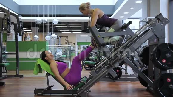 健身女士正在和女朋友一起在健身房做腿部按压视频的预览图