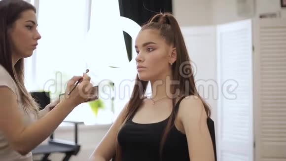 化妆师用雀斑的年轻红发女人做职业化妆视频的预览图