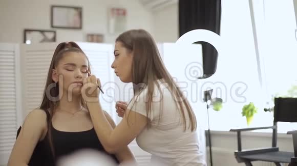 化妆师用雀斑的年轻红发女人做职业化妆视频的预览图