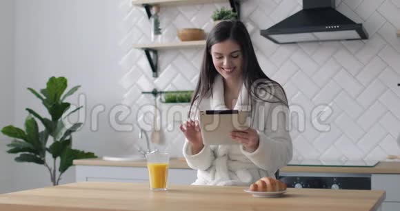 快乐女孩在厨房里用平板电脑视频的预览图