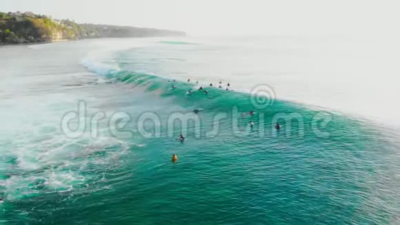 热带海洋中绿松石桶状波的鸟瞰图和排队的冲浪者视频的预览图