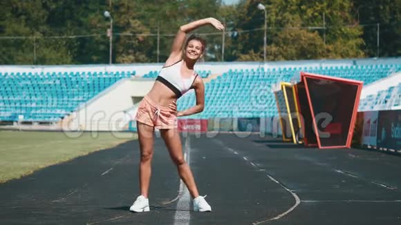 运动户外运动在体育场做伸展运动的女孩弯到一边去视频的预览图
