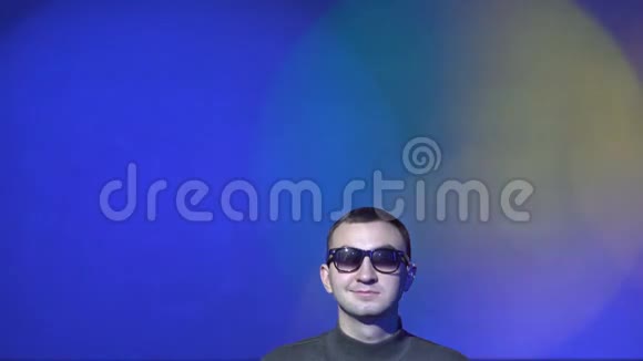 一个迷人的男人在灯光多色背景上的肖像视频的预览图