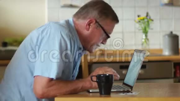 一个男人在家里用他的笔记本电脑工作公平地搓手对结果好消息远程就业视频的预览图