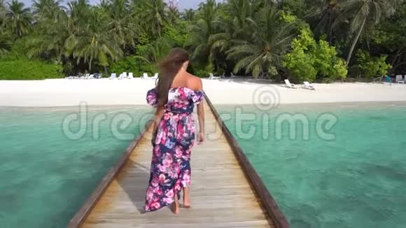 马尔代夫的女子在沙滩上用手掌和纯净的海水在桥上行走视频的预览图
